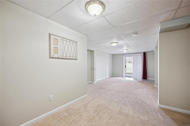 below grade area featuring a paneled ceiling, baseboards, and carpet floors