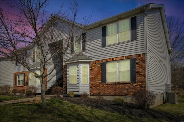 traditional-style house featuring central air condition unit and brick siding