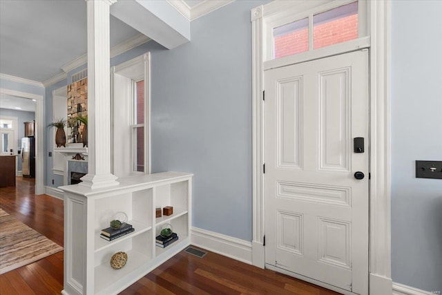 foyer with decorative columns, dark wood-style floors, baseboards, and ornamental molding