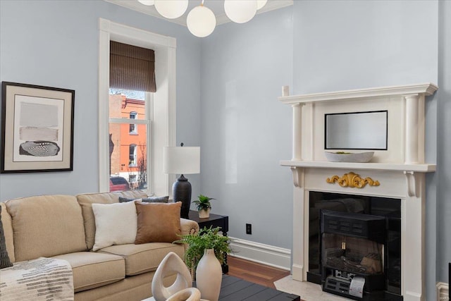 living room with baseboards, wood finished floors, and a fireplace with flush hearth