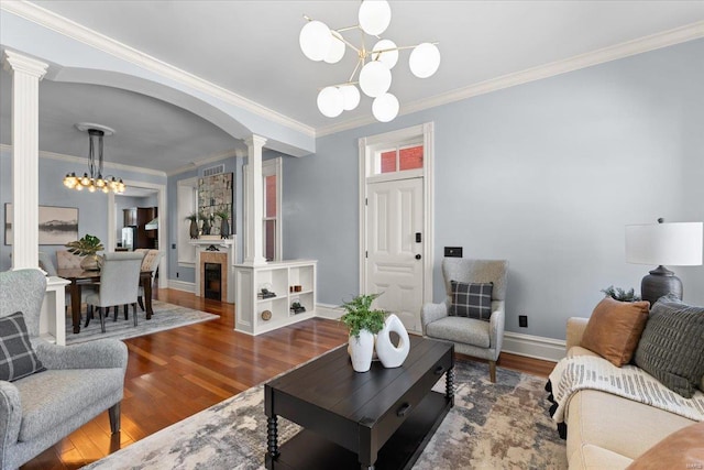 living area with decorative columns, an inviting chandelier, and wood finished floors