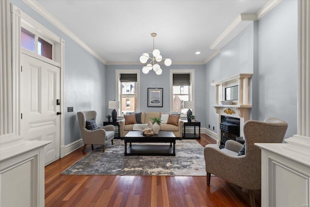 living area featuring a glass covered fireplace, baseboards, a notable chandelier, and wood finished floors