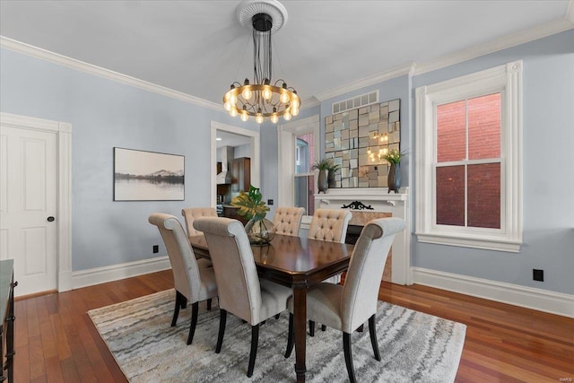 dining space with a chandelier, ornamental molding, baseboards, and wood finished floors