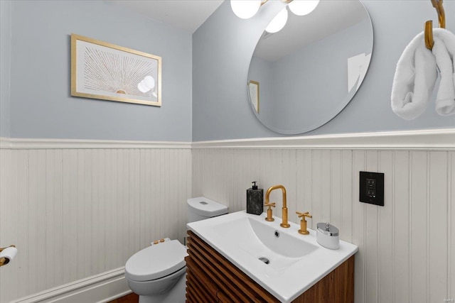 bathroom featuring vanity, toilet, and wainscoting