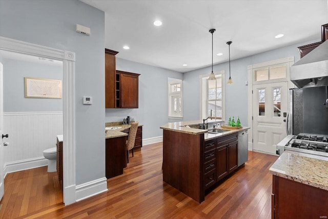 kitchen featuring a sink, stove, dark wood-type flooring, dishwasher, and wall chimney exhaust hood