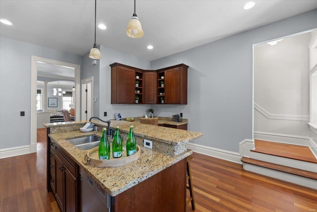 kitchen with dark wood-style floors, dishwashing machine, hanging light fixtures, and a sink