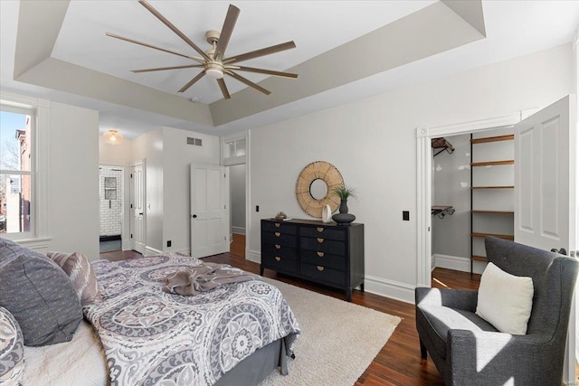 bedroom with a raised ceiling, dark wood-style floors, visible vents, and baseboards