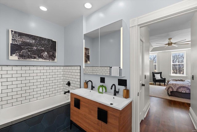 ensuite bathroom with a sink, connected bathroom, wood finished floors, and a bath