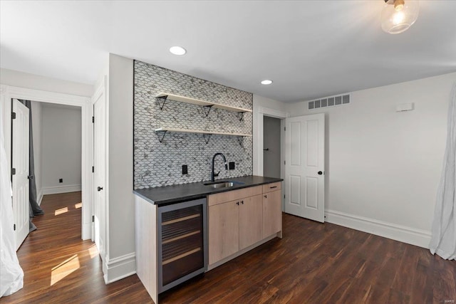 bar featuring dark wood-style floors, beverage cooler, visible vents, a sink, and decorative backsplash