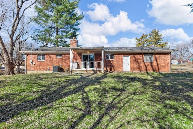 rear view of property with a yard, cooling unit, brick siding, and a chimney