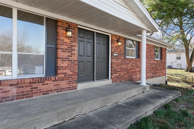 entrance to property featuring brick siding and covered porch