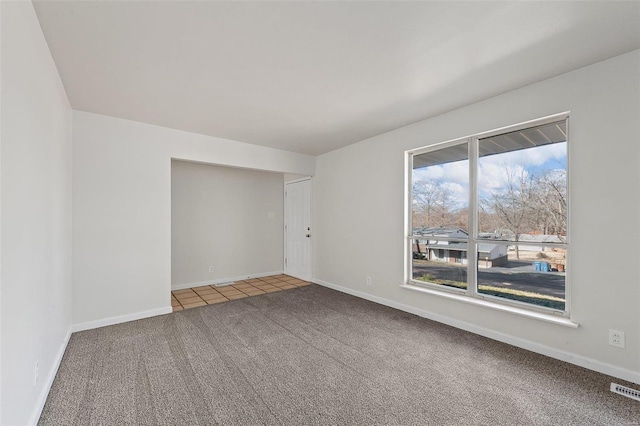 spare room featuring tile patterned floors, carpet flooring, visible vents, and baseboards