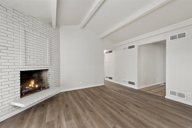 unfurnished living room with visible vents, a brick fireplace, and wood finished floors