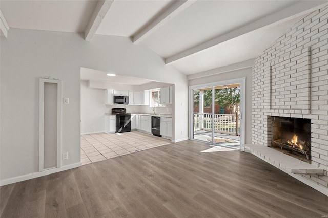 unfurnished living room featuring light wood-type flooring, baseboards, a fireplace, and vaulted ceiling with beams