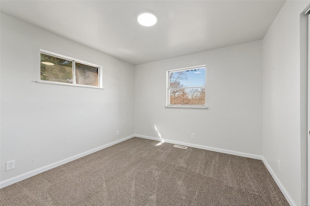 empty room featuring baseboards and dark carpet