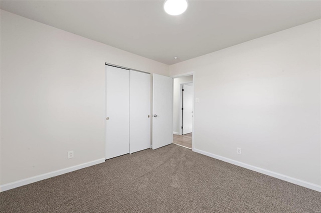 unfurnished bedroom with a closet, baseboards, and carpet flooring