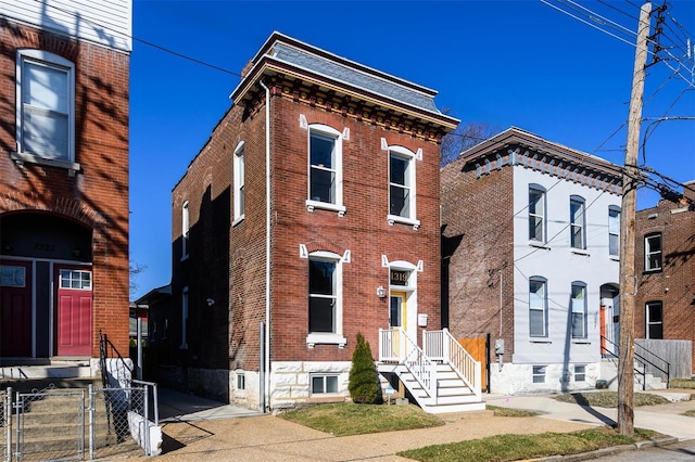 view of front facade featuring a gate, fence, and brick siding