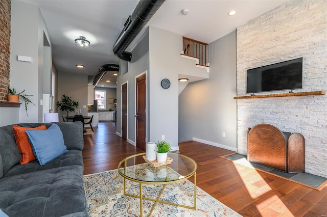 living room with a fireplace with flush hearth, baseboards, and wood finished floors