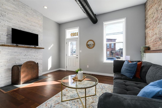 living room with a fireplace, dark wood-type flooring, and baseboards