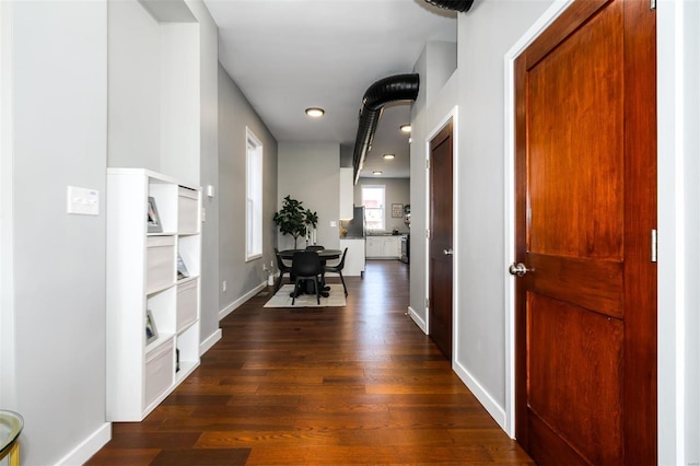 hallway with dark wood-type flooring and baseboards