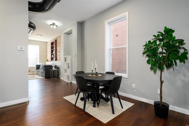 dining area featuring dark wood-style floors, built in shelves, and baseboards