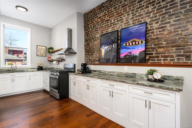 kitchen featuring stone counters, a sink, dark wood-type flooring, wall chimney range hood, and stainless steel gas stove