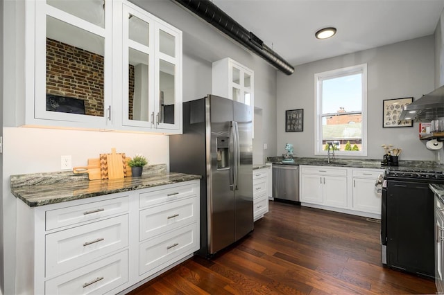 kitchen featuring stone counters, dark wood-style flooring, stainless steel appliances, glass insert cabinets, and white cabinetry