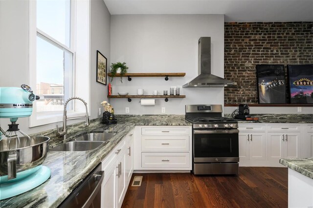 kitchen with a sink, light stone counters, dark wood-style floors, stainless steel appliances, and wall chimney range hood