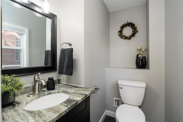 bathroom featuring vanity, toilet, and baseboards