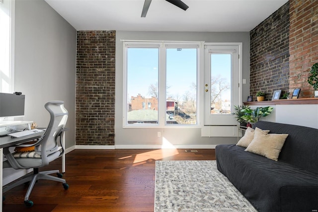 home office with brick wall, a ceiling fan, baseboards, and wood finished floors