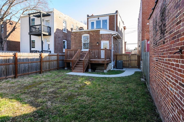 back of house featuring a yard, brick siding, central AC unit, and a fenced backyard