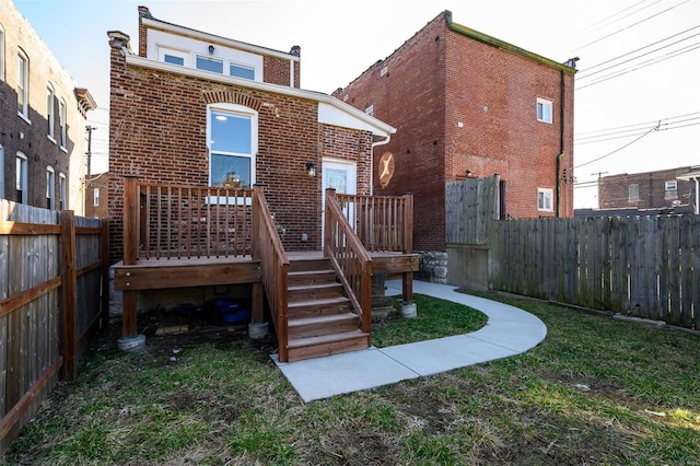 rear view of property featuring brick siding and a fenced backyard