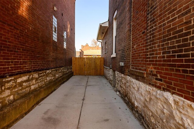 view of side of home featuring brick siding, a patio area, and fence