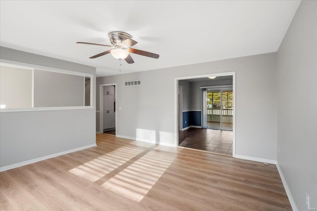 unfurnished room with visible vents, baseboards, ceiling fan, and wood finished floors