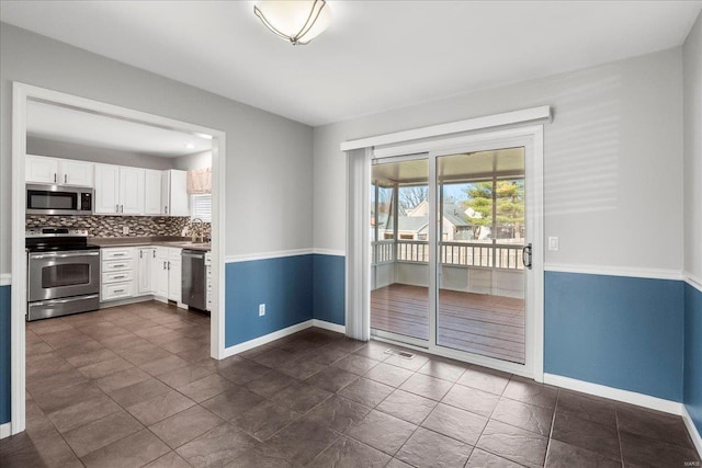 kitchen with stainless steel appliances, baseboards, tasteful backsplash, and white cabinetry