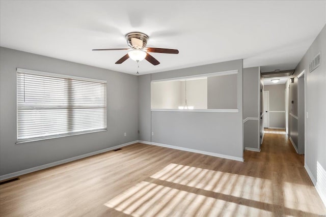 empty room with visible vents, baseboards, a ceiling fan, and wood finished floors