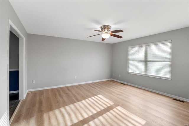 spare room featuring visible vents, light wood-style flooring, baseboards, and ceiling fan