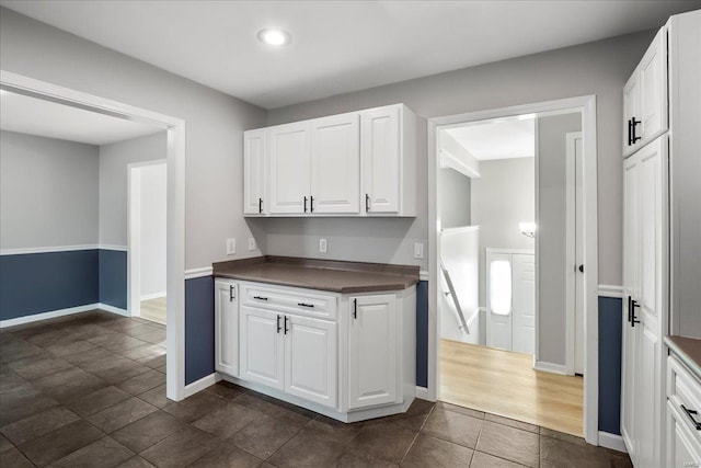 kitchen with white cabinetry, dark countertops, and baseboards