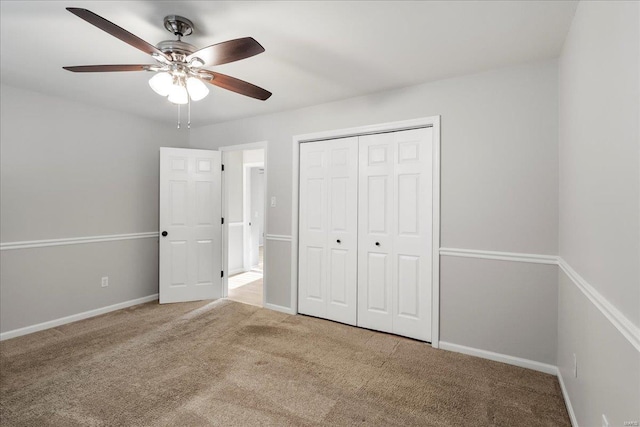 unfurnished bedroom with a closet, baseboards, carpet, and a ceiling fan