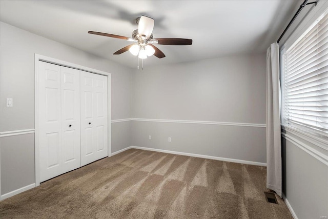 unfurnished bedroom with visible vents, a ceiling fan, a closet, carpet flooring, and baseboards