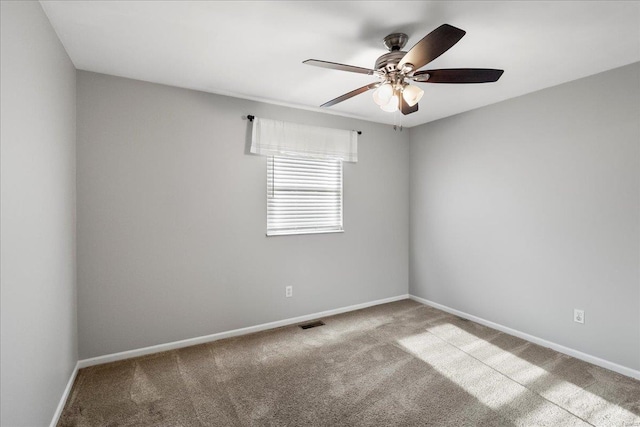 carpeted empty room with visible vents, baseboards, and a ceiling fan