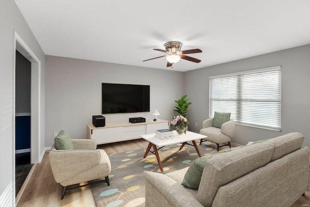 living room with ceiling fan, baseboards, and wood finished floors