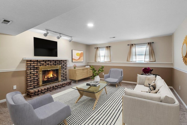 living area featuring carpet, visible vents, baseboards, a textured ceiling, and a brick fireplace