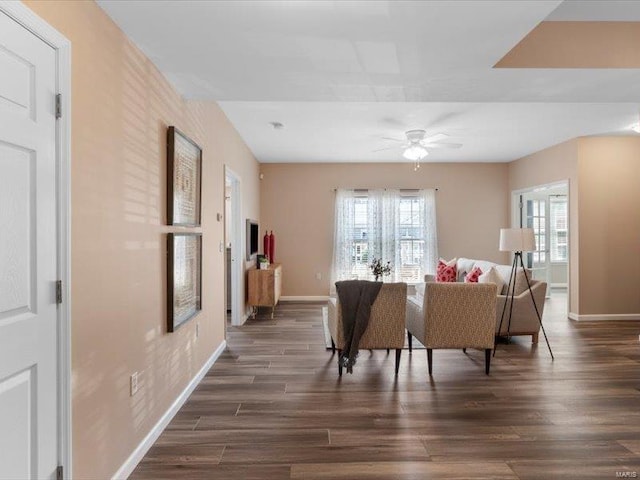 living room featuring ceiling fan, baseboards, and wood finished floors