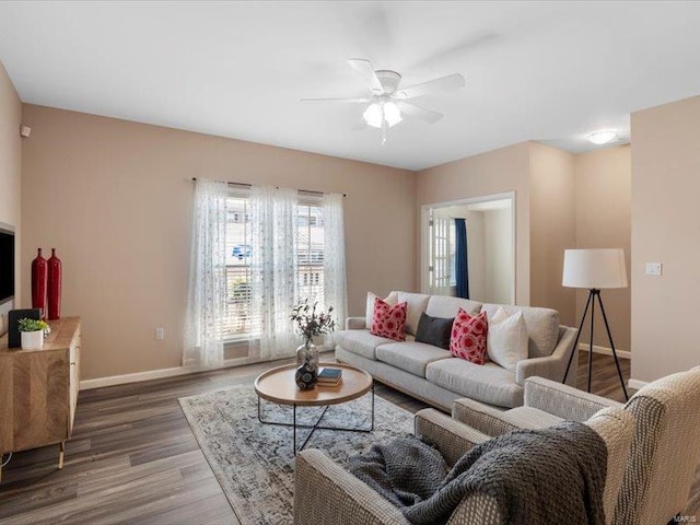 living area with a ceiling fan, wood finished floors, and baseboards