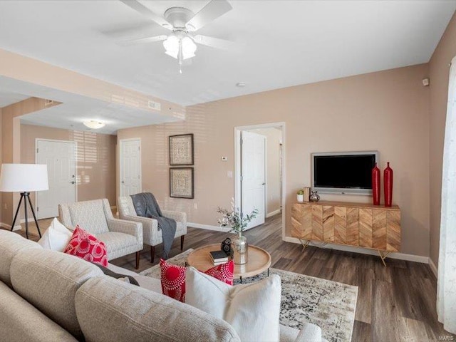 living room with ceiling fan, baseboards, and wood finished floors