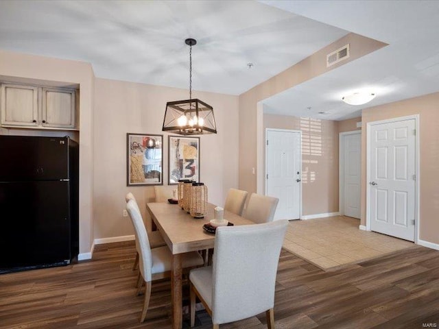 dining room featuring visible vents, baseboards, and wood finished floors