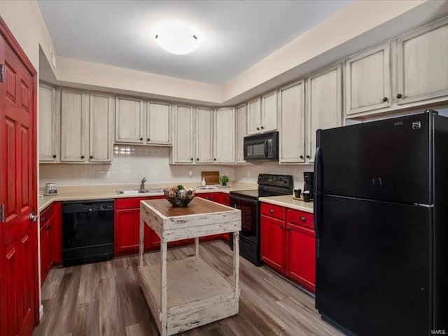 kitchen with dark wood-type flooring, black appliances, a sink, tasteful backsplash, and light countertops