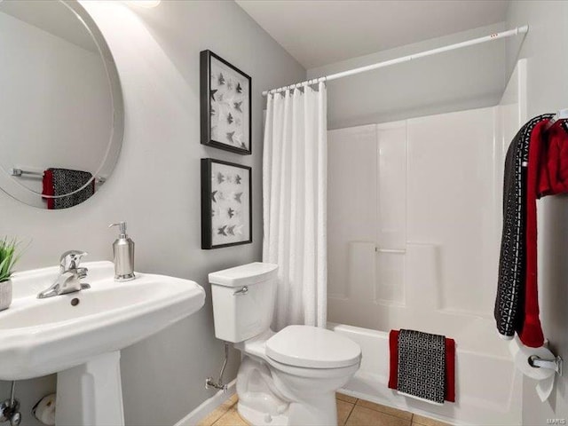 bathroom featuring tile patterned floors, shower / bath combo with shower curtain, toilet, and a sink