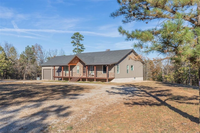 view of front of property featuring an attached garage, a porch, and dirt driveway